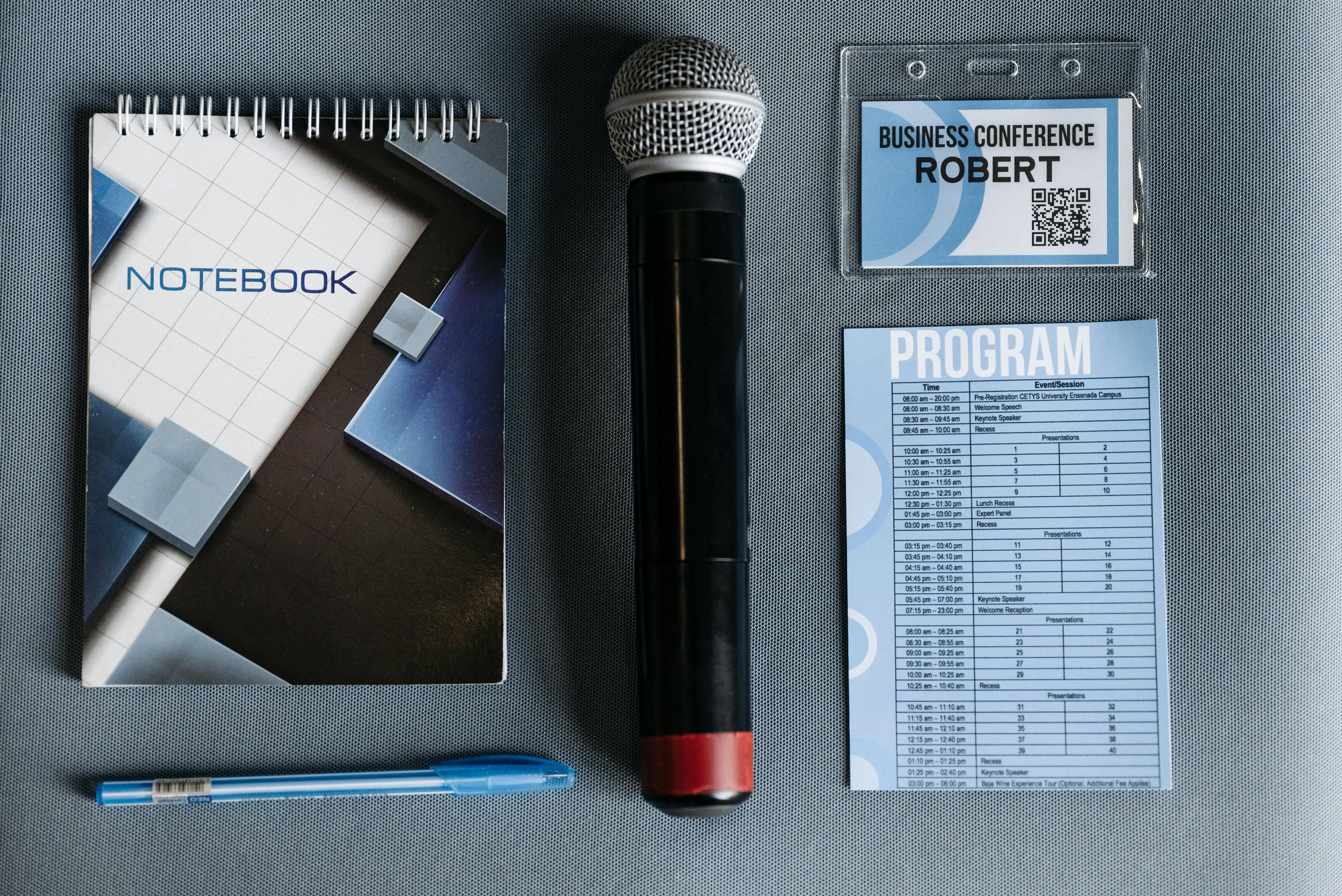 Flat lay of conference essentials including microphone, notebook, and program.